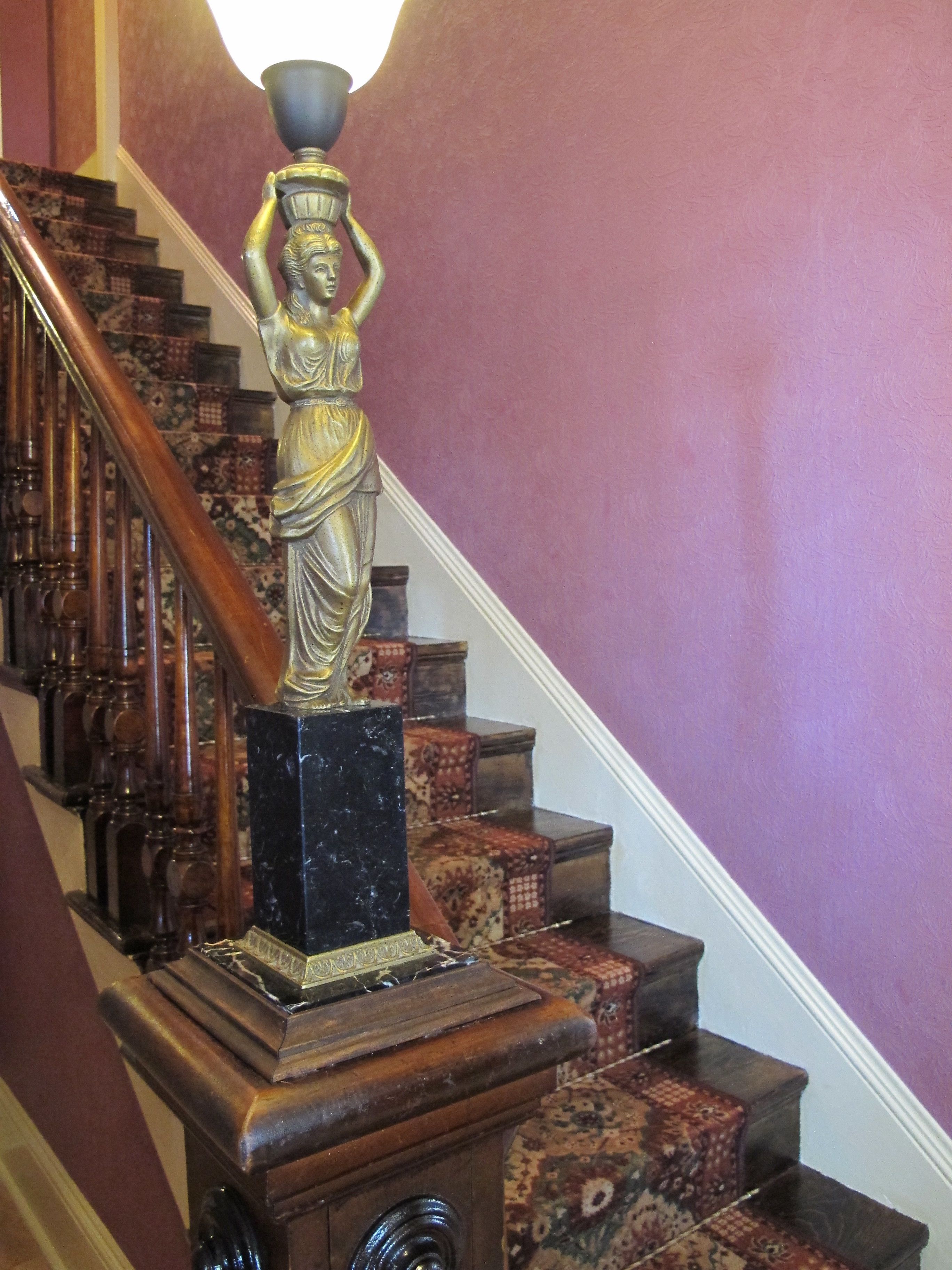 A staircase with a statue on the top of the banister.