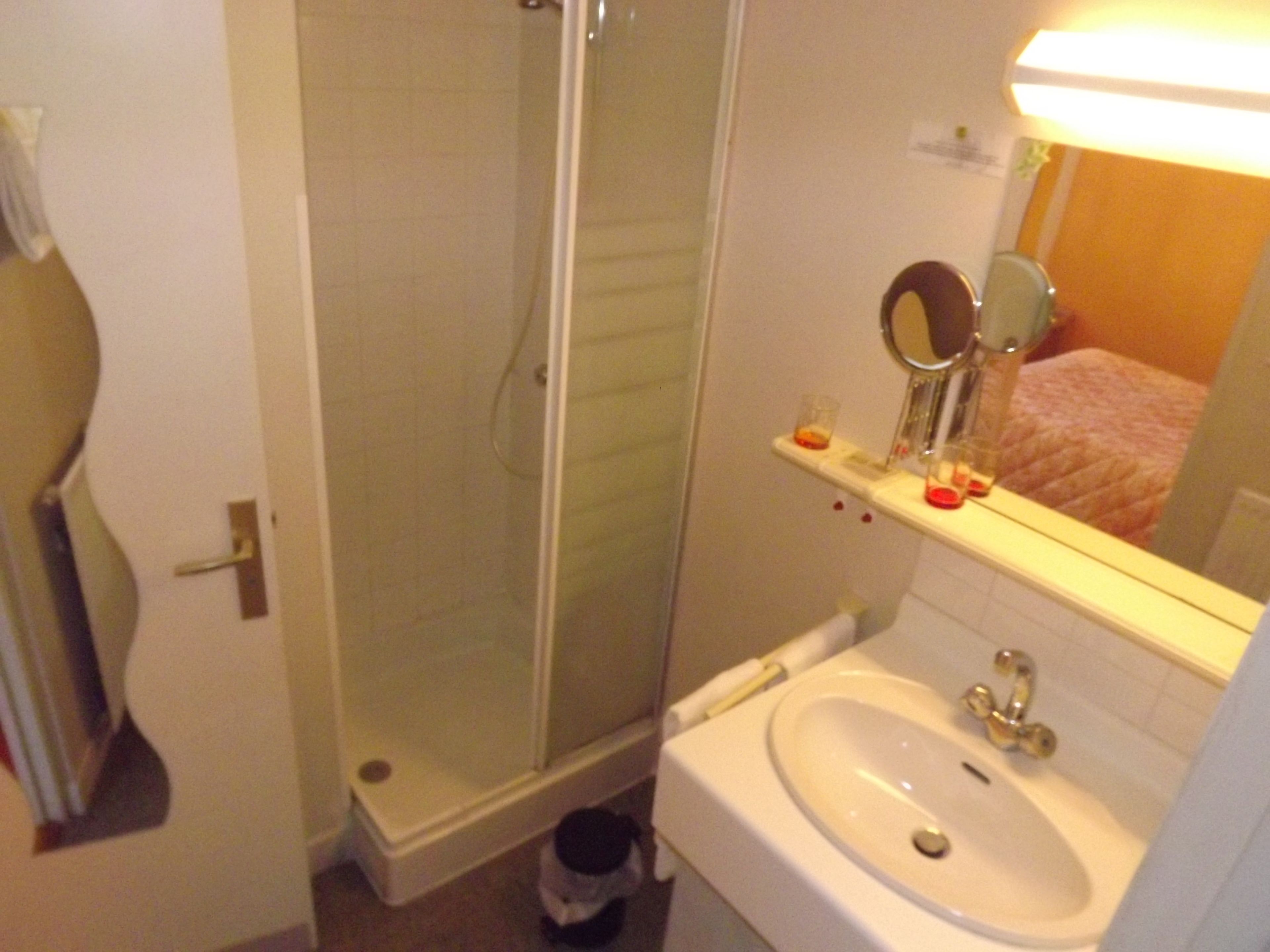 A bathroom with a glass shower enclosure, a sink with a mirror, and a toilet.