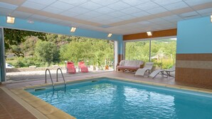 A swimming pool with a view of trees and hills, surrounded by lounge chairs and a covered area with a ceiling. - Hostellerie des Lauriers (Curvalle)
