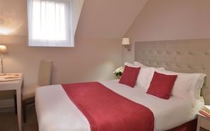 Habitación de hotel con una cama grande, una mesita de noche, una lámpara y una ventana con cortinas.