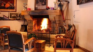 Una sala de estar acogedora con chimenea, muebles de madera y diversos objetos decorativos.