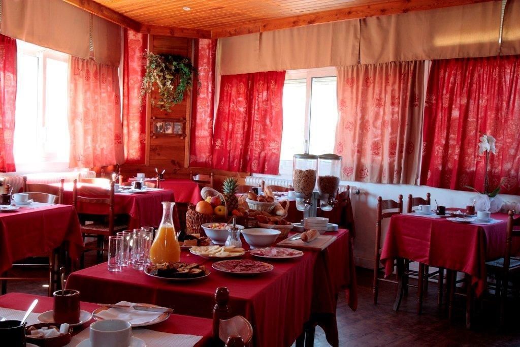 A dining area with red curtains, wooden walls, and tables set for breakfast.