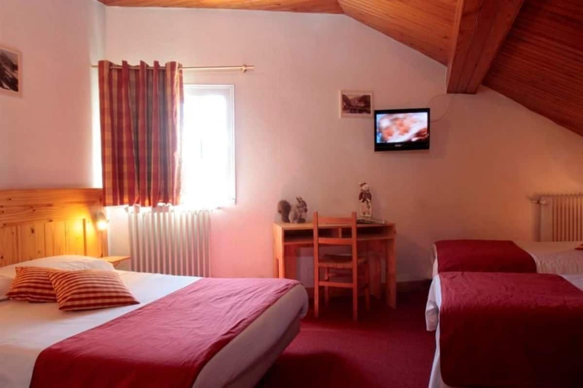 A cozy room with two beds, a desk, and a TV.