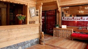 Un interior de madera con una recepción, una estatua de madera y un banco rojo.