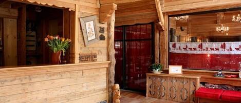 A wooden interior with a reception desk, a wooden statue, and a red bench.