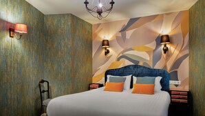 Une chambre d’hôtel avec un grand lit, deux tables de chevet, un lustre et des lampes fixées au mur.