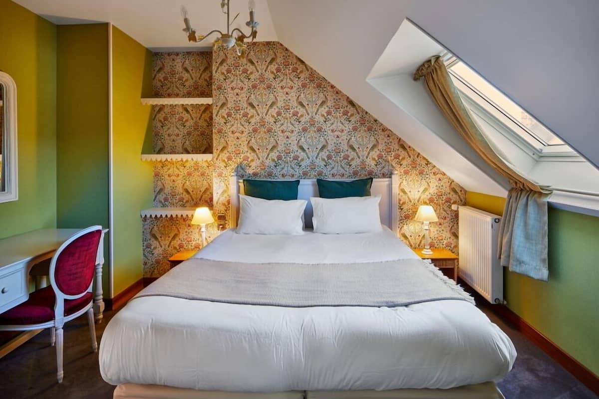 Une chambre à coucher avec un grand lit, deux lampes de chevet, un bureau et une chaise.