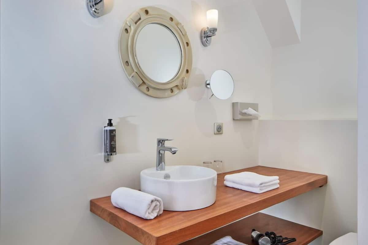 Une salle de bain moderne avec un grand miroir rond, deux vasques et un meuble-lavabo en bois.