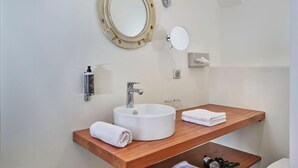 Une salle de bain moderne avec un grand miroir rond, deux vasques et un meuble-lavabo en bois.