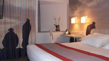 A hotel room with a bed, a desk, a chair, and a window.