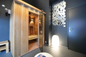 A modern bathroom with a wooden sauna, a wall-mounted mirror arrangement, and a bright light fixture. - Best Western Auray Le Loch (Auray)