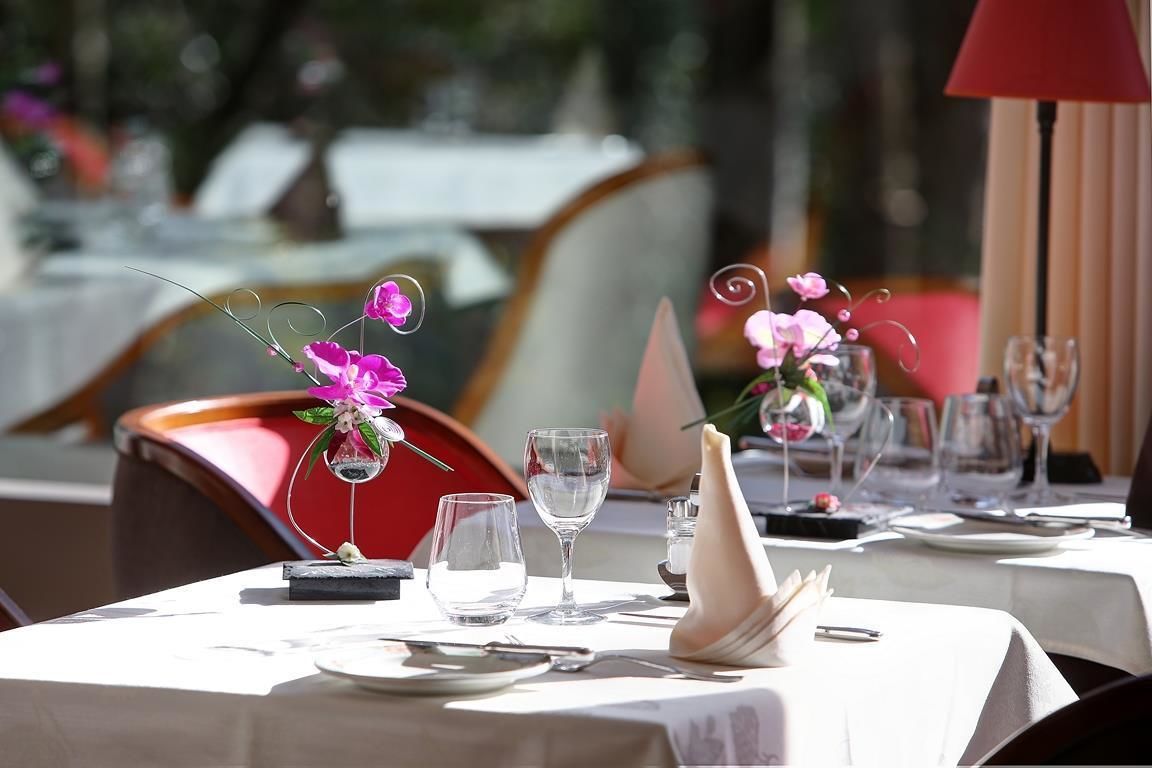 A table set for dining with a vase of pink flowers, clear glasses, and a menu.