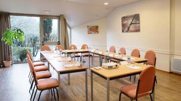 A conference room with a long table, chairs, a projector, and a window with a view of trees.