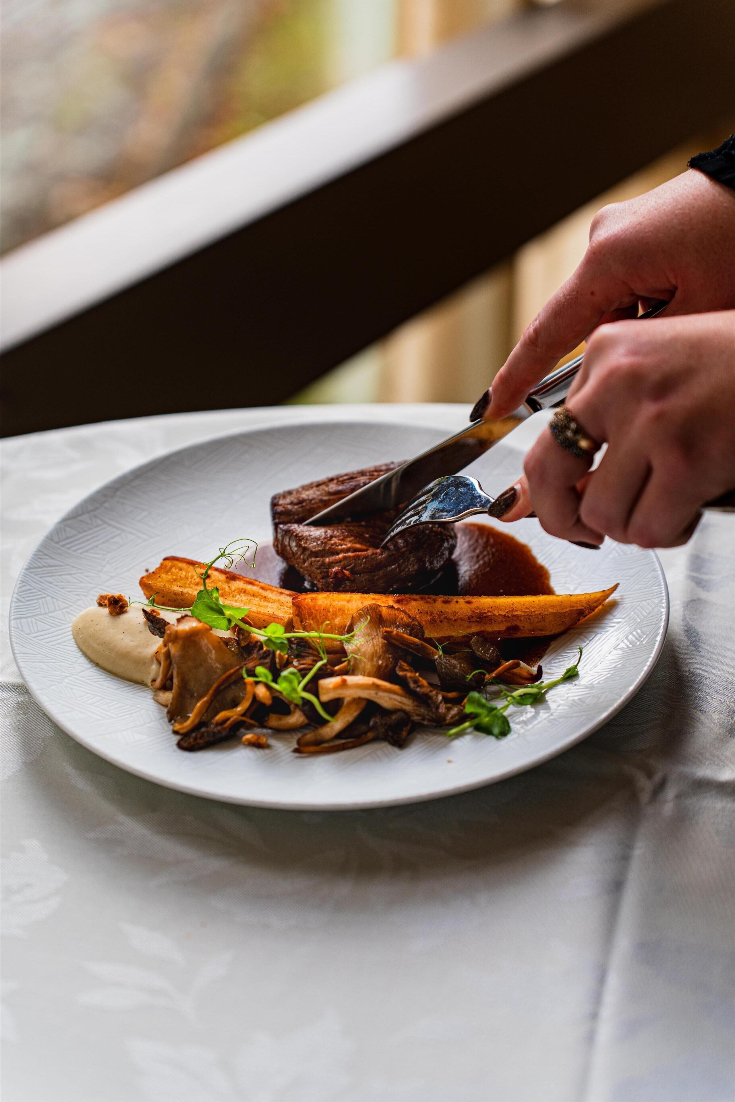 A plate of food with a person using a fork and knife.