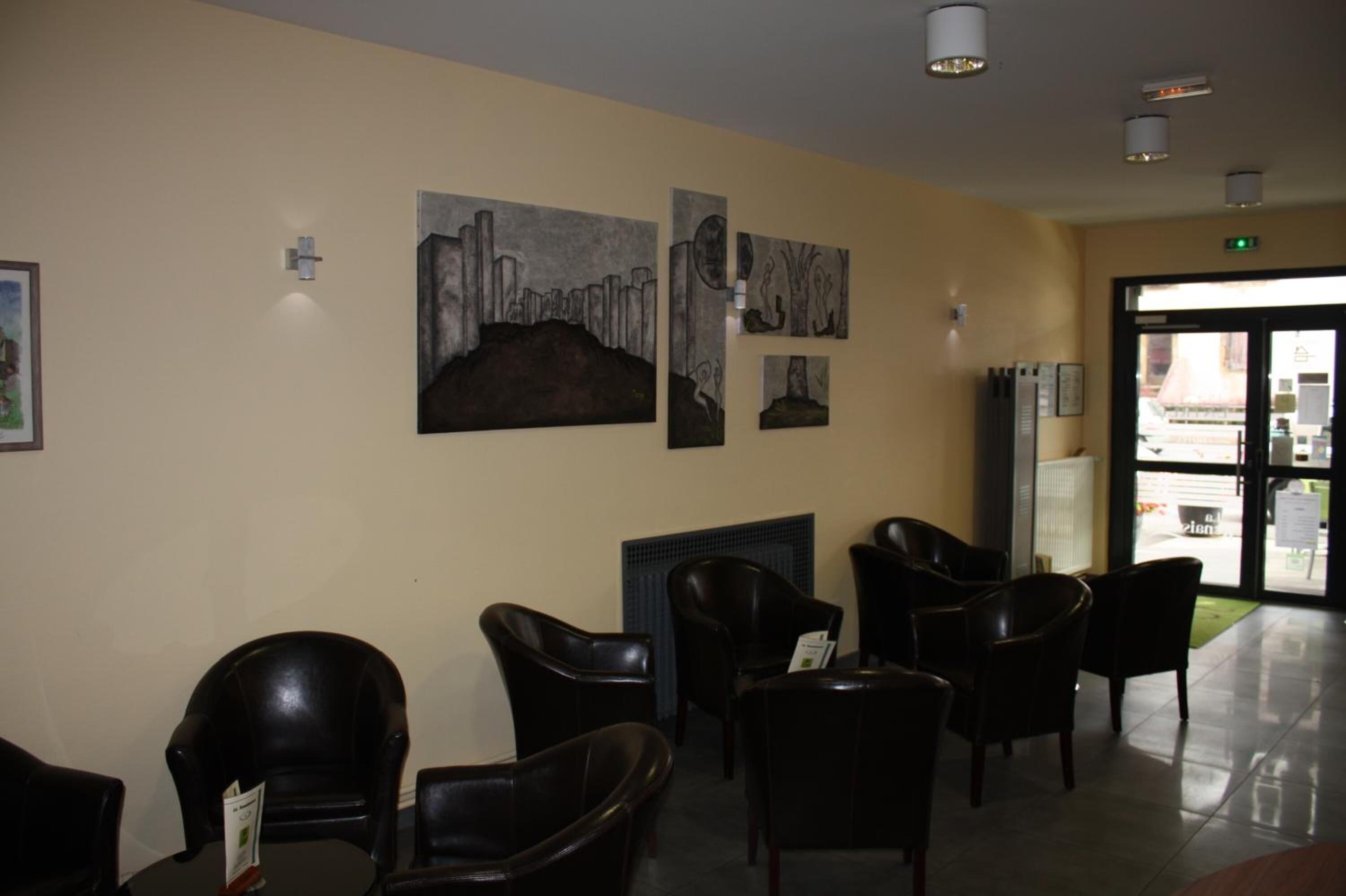 A reception area with black leather chairs, a fireplace, and wall art.