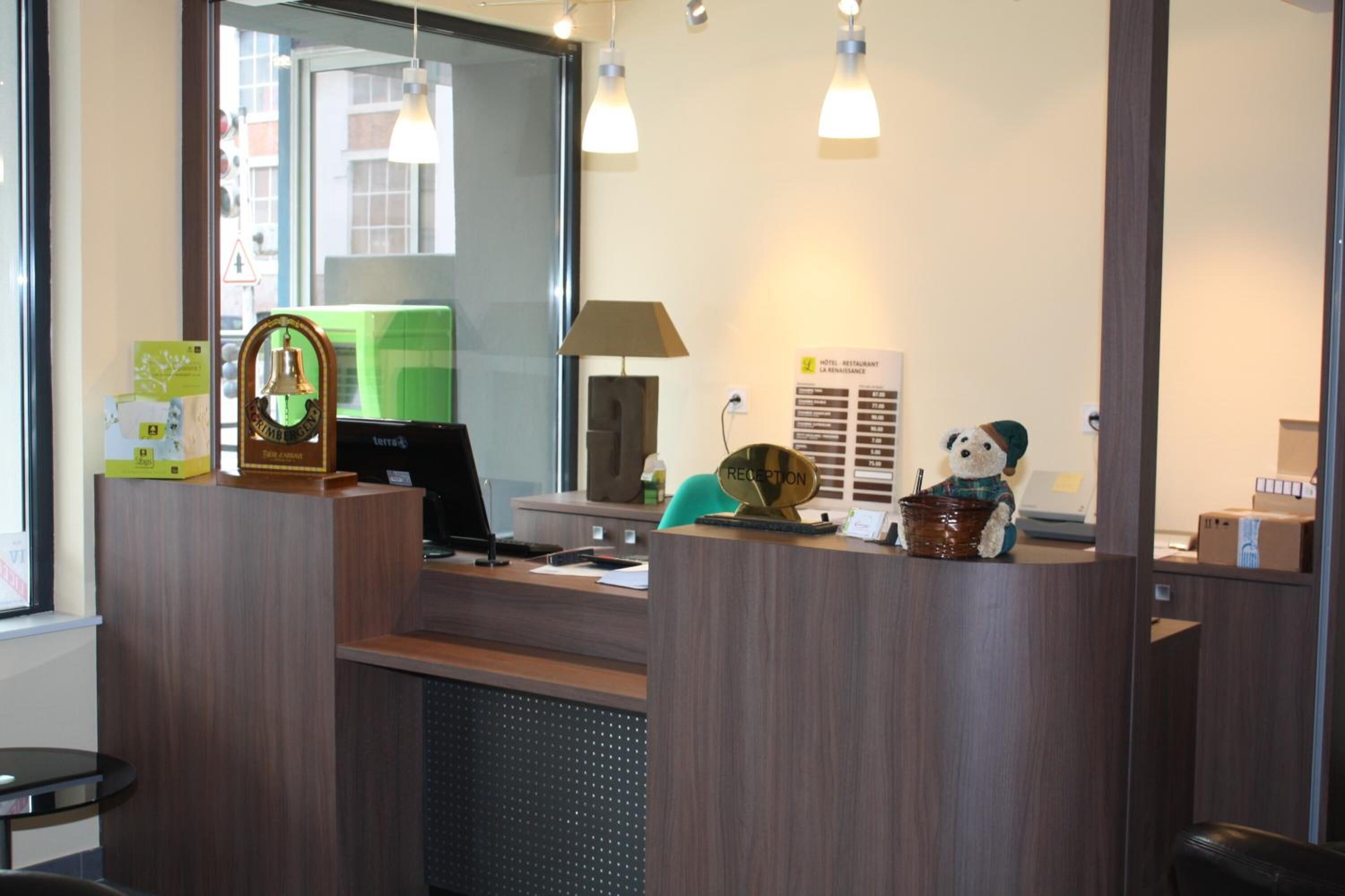 Ein Hotelrezeptionstresen mit Computer, Lampe und Speisekarte.