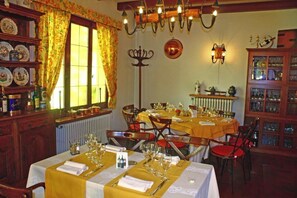 A dining area with a table set for four, a chandelier, and a window with curtains.