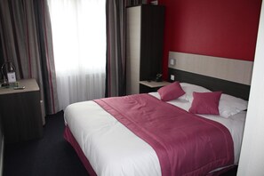 A hotel room with a bed, a nightstand, a desk, and a wardrobe.