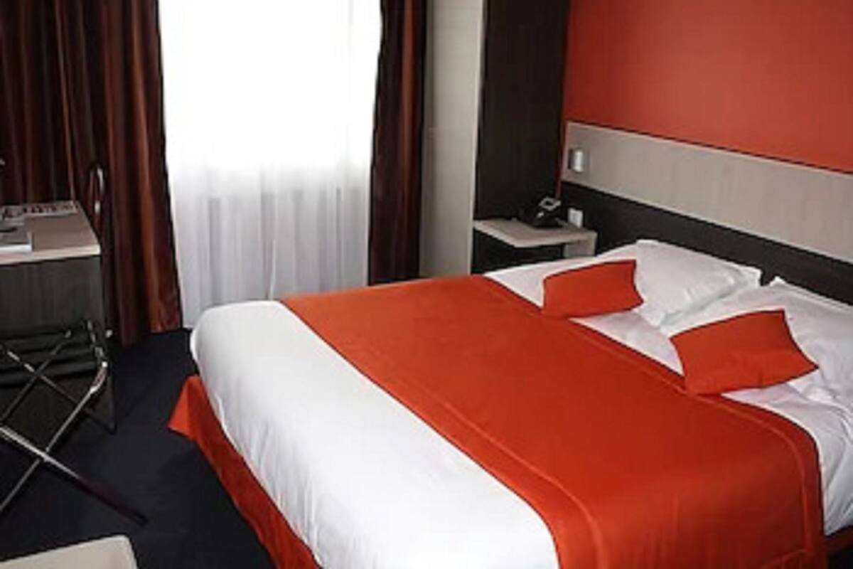 A hotel room with a large bed, a desk, and a chair.
