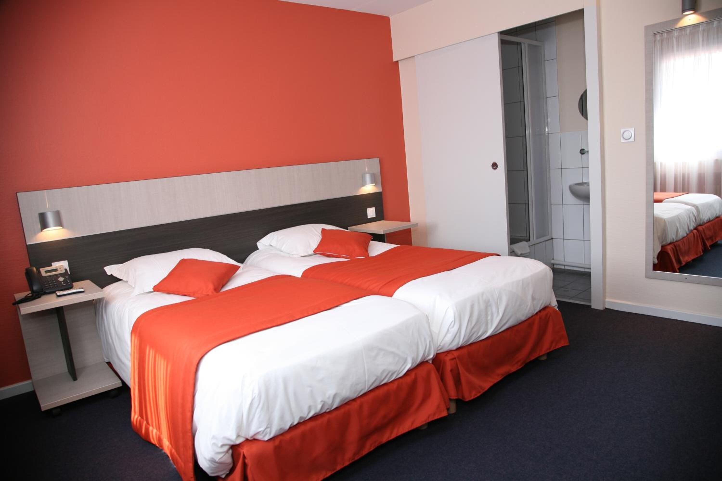 A hotel room with a large bed, a bedside table with a lamp, and a mirror.