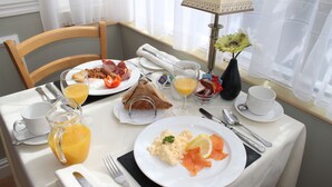 A breakfast table with plates of eggs, bacon, toast, and juice. - The Baytree (Torquay)