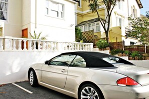 A white convertible car parked in front of a building with a white fence and a balcony. - The Baytree (Torquay)