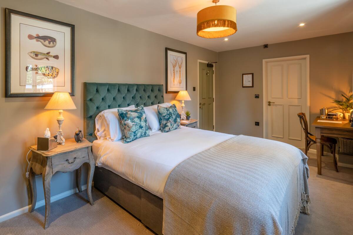 A bedroom with a large bed, two bedside tables, a desk, and a chair.