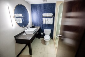 Une salle de bain moderne avec un grand miroir, un lavabo, des toilettes et un porte-serviettes.