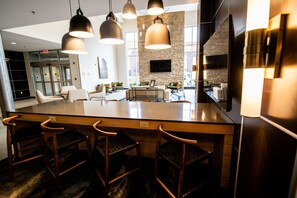 Une cuisine moderne dotée d’un îlot central, de luminaires suspendus et d’un mur d’accent en pierre.