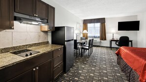 A compact hotel room with a kitchenette, a dining area, a bed, and a TV. - SureStay Plus Hotel by Best Western Lubbock Medical Center (Lubbock)