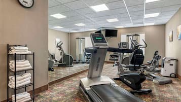 Un gimnasio de hotel con cinta de correr, elíptica y bicicletas estáticas.