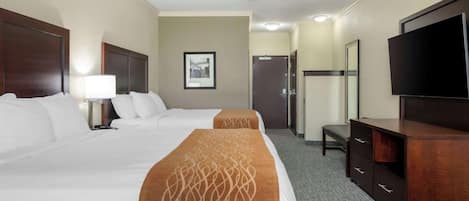Habitación de hotel con dos camas, un escritorio, un televisor y un ventilador de techo.