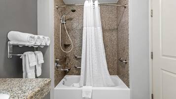 A bathroom with a shower, a bathtub, and a granite countertop.