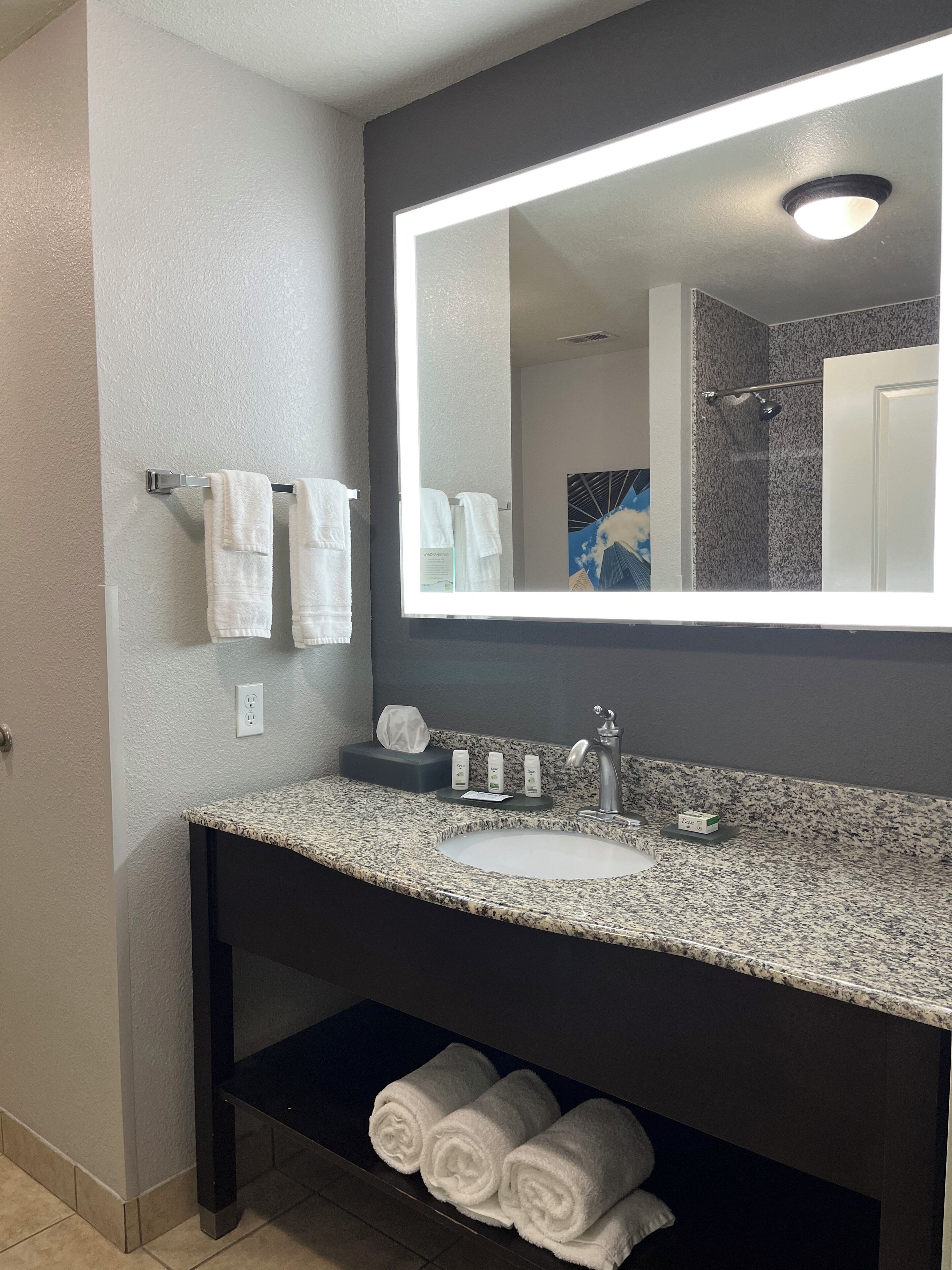A bathroom with a granite countertop, a sink, a mirror, and a towel rack.
