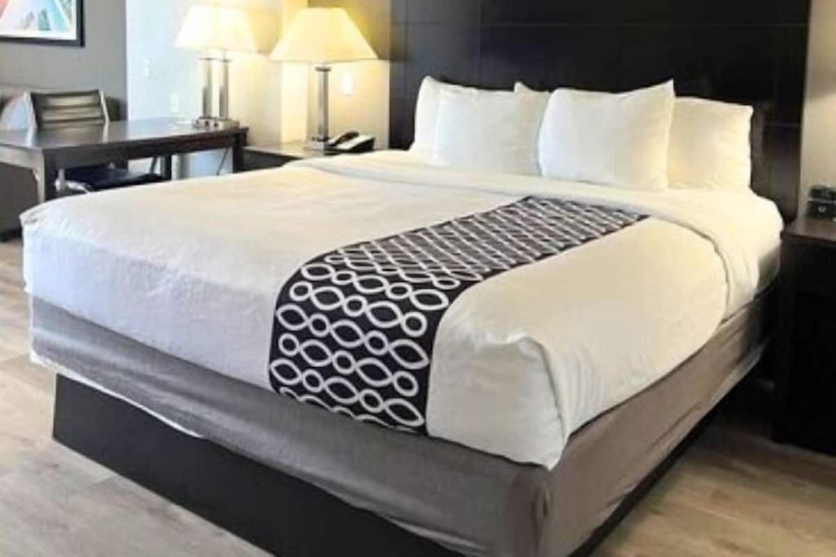 A modern hotel room with a large bed, two bedside lamps, a desk, and a chair.