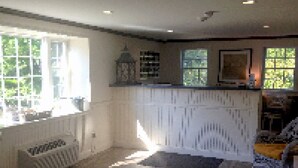 A spacious kitchen with white cabinetry, a large window, and a view of the outdoors. - Craigville Beach Inn (Centerville)