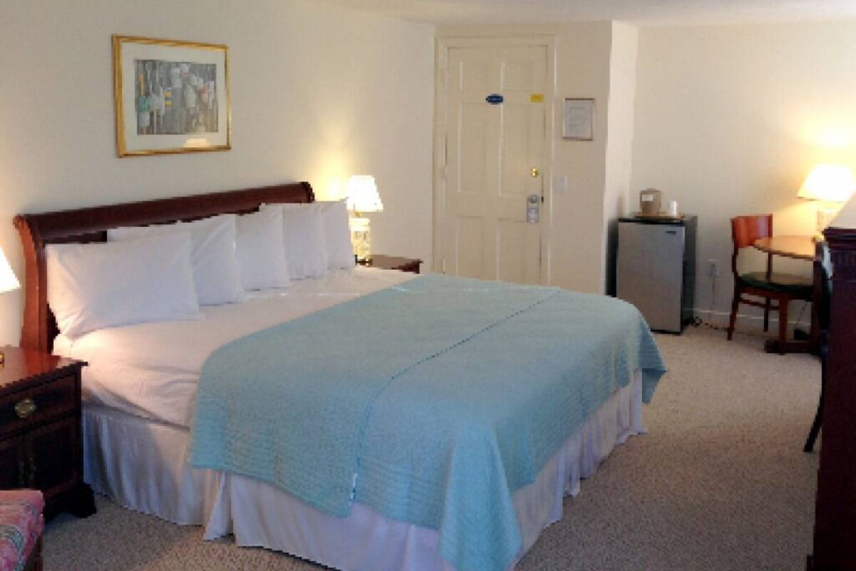 Une chambre d’hôtel bien rangée, avec un lit, des tables de chevet, un bureau et une chaise.