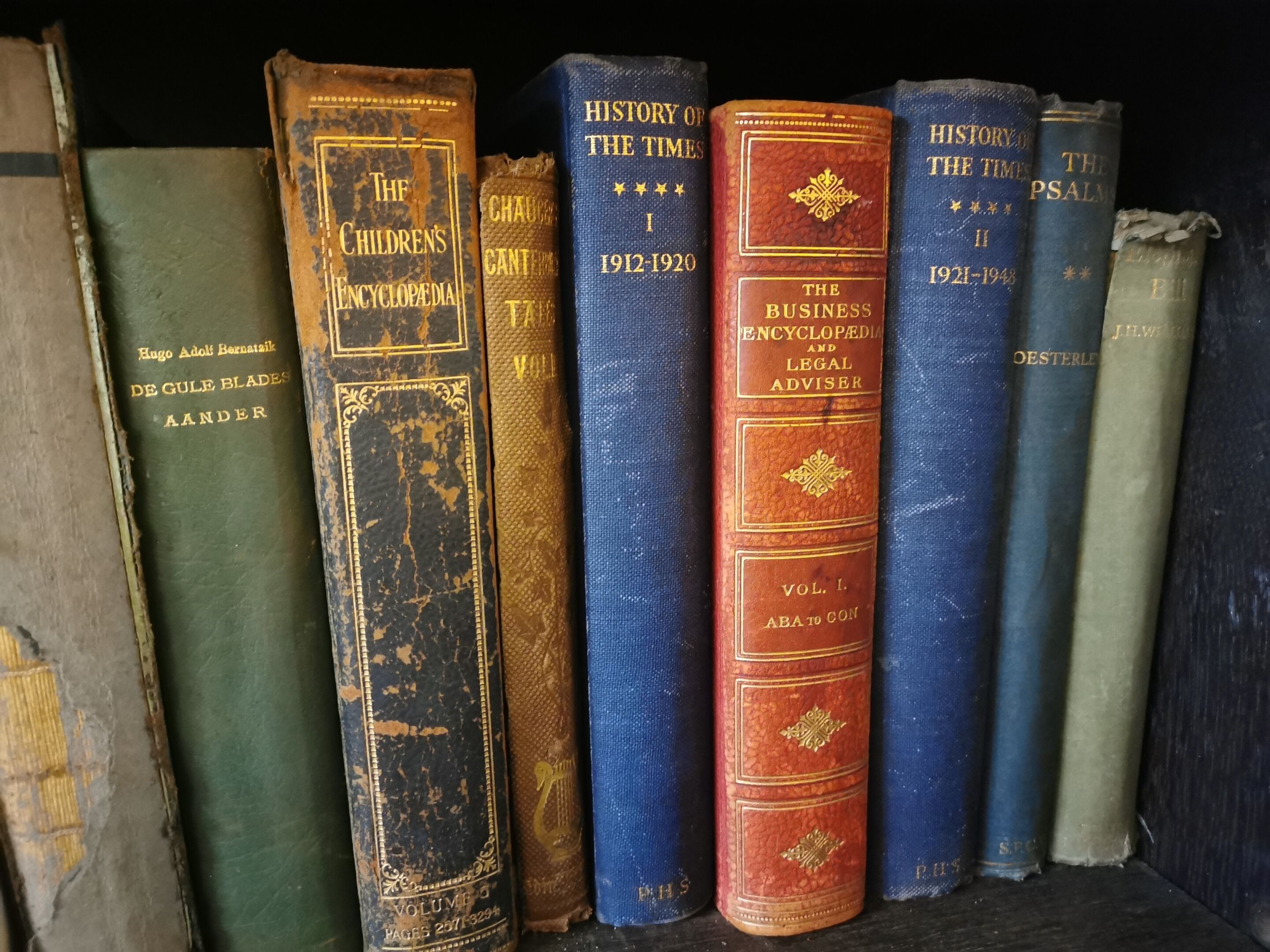 A collection of old, worn books on a shelf.