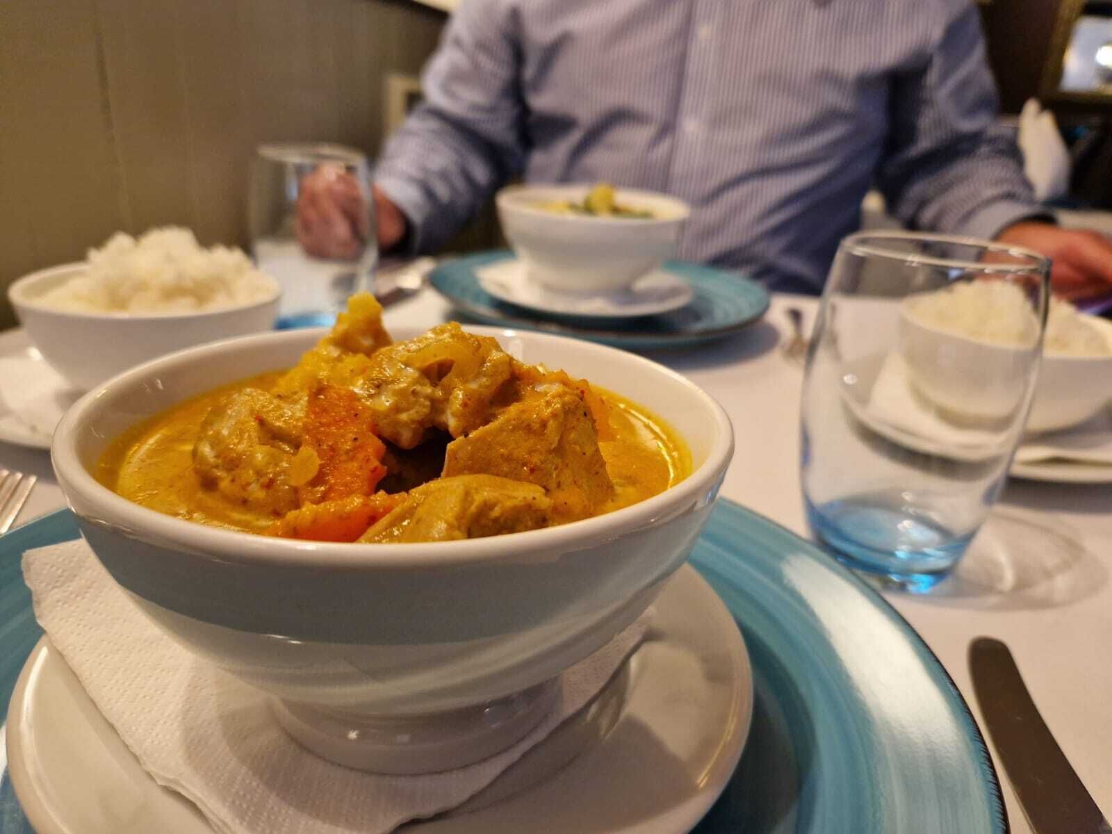 A bowl of curry with rice on a table.