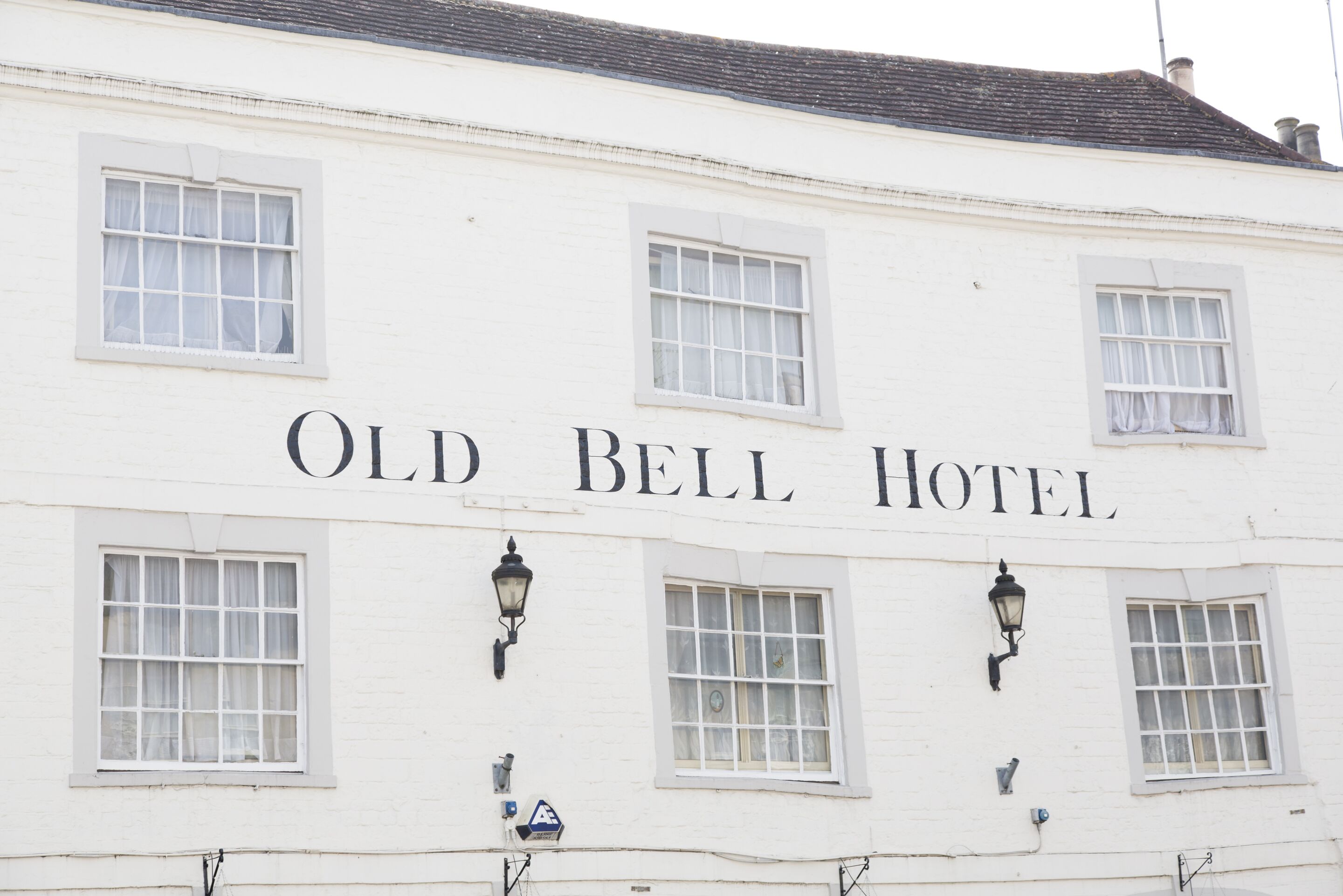 Un edificio blanco con el letrero 'Old Bell Hotel' sobre las ventanas.