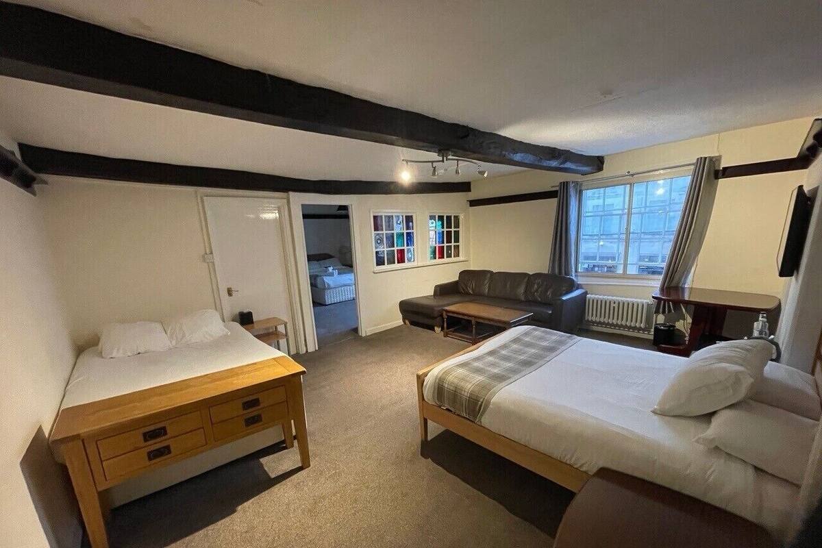 A bedroom with a bed, a wooden dresser, a sofa, and a window with curtains.