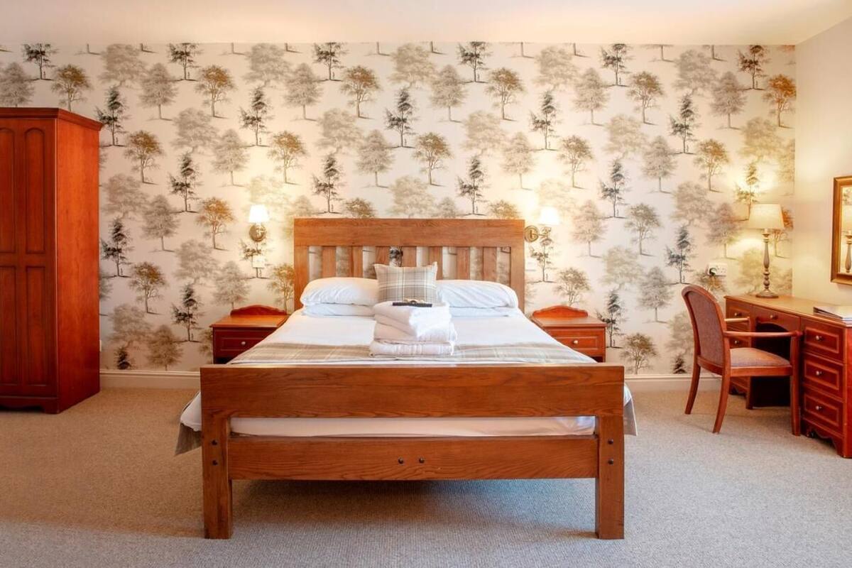 A bedroom with a wooden bed, nightstands, a desk, and a chair.