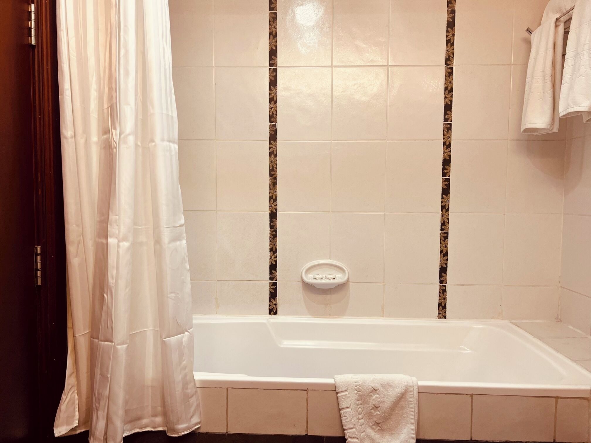 A bathroom with a bathtub, a shower curtain, and a towel rack.