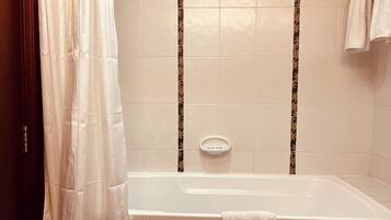 A bathroom with a bathtub, a shower curtain, and a towel rack.