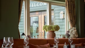 L’intérieur d’un restaurant, avec une enseigne accueillante, un canapé et une table mise avec des verres.