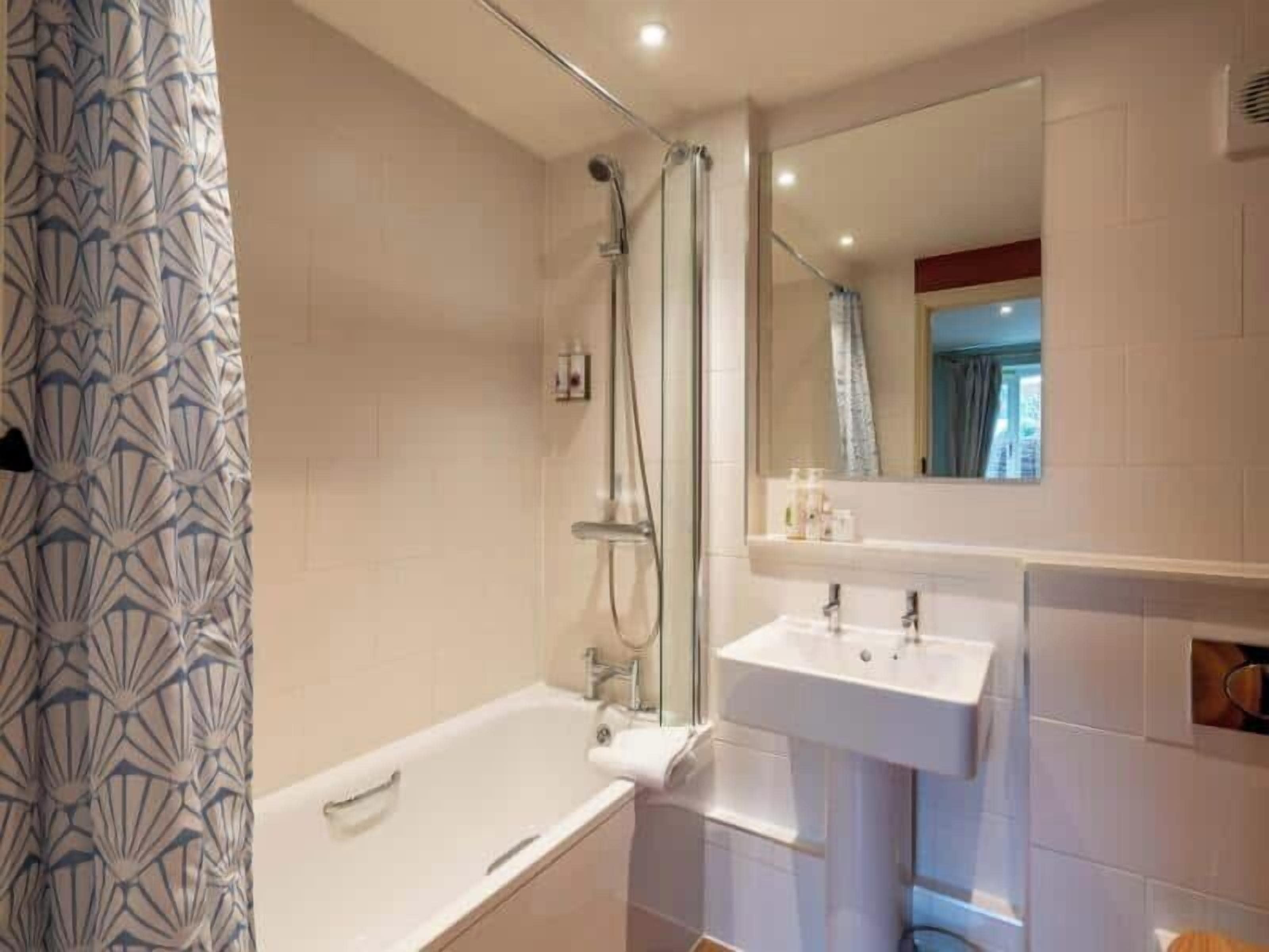 A bathroom with a bathtub, a shower, a sink, and a mirror.