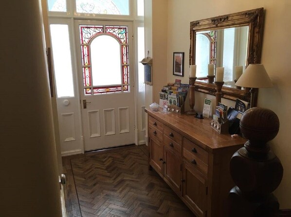 A wooden vanity with a mirror, a door with stained glass, and a herringbone floor. - The Whalebone Arch (Whitby)