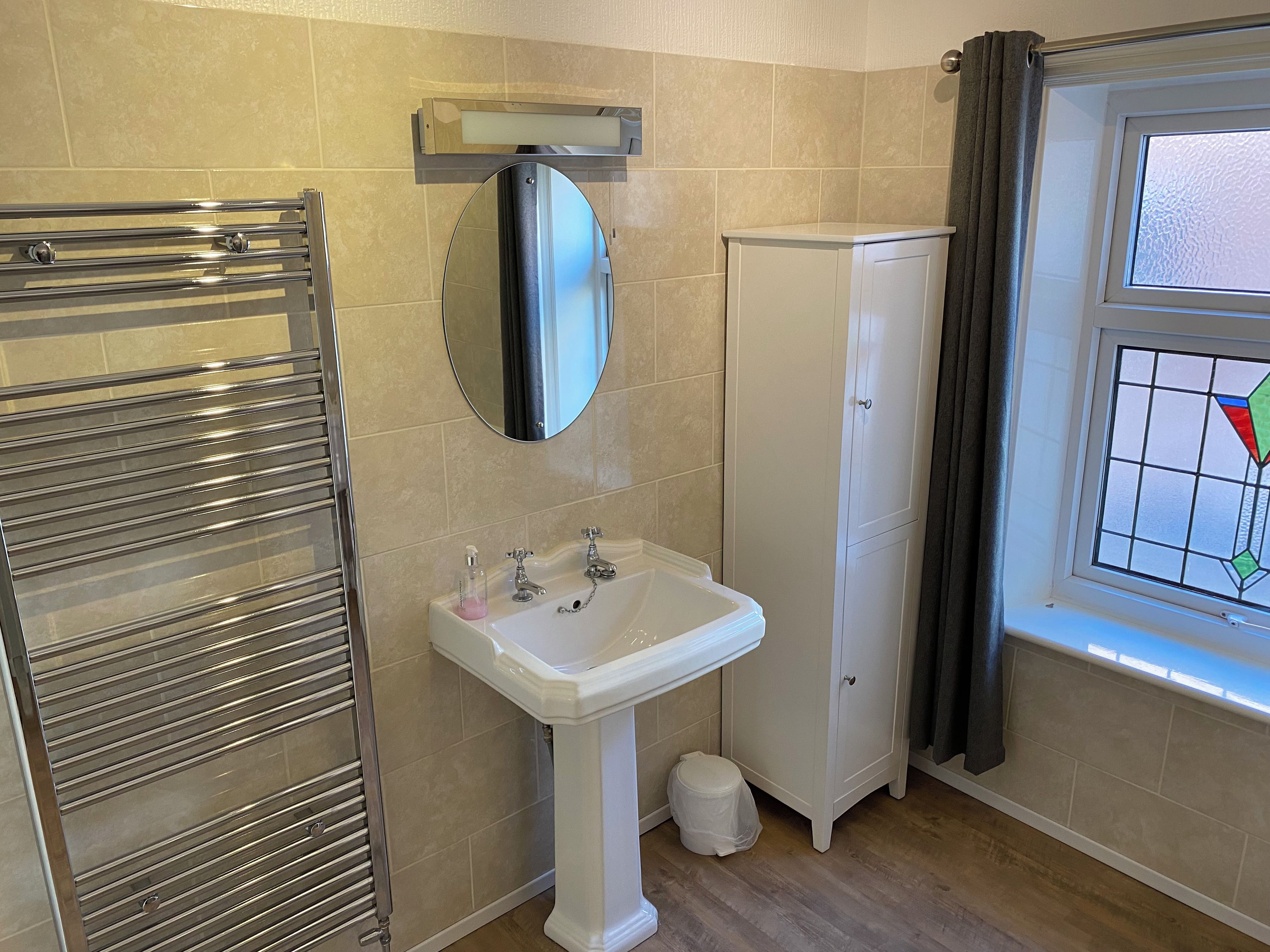 Un baño con cabina de ducha de vidrio, un lavabo blanco, un espejo y un armario.