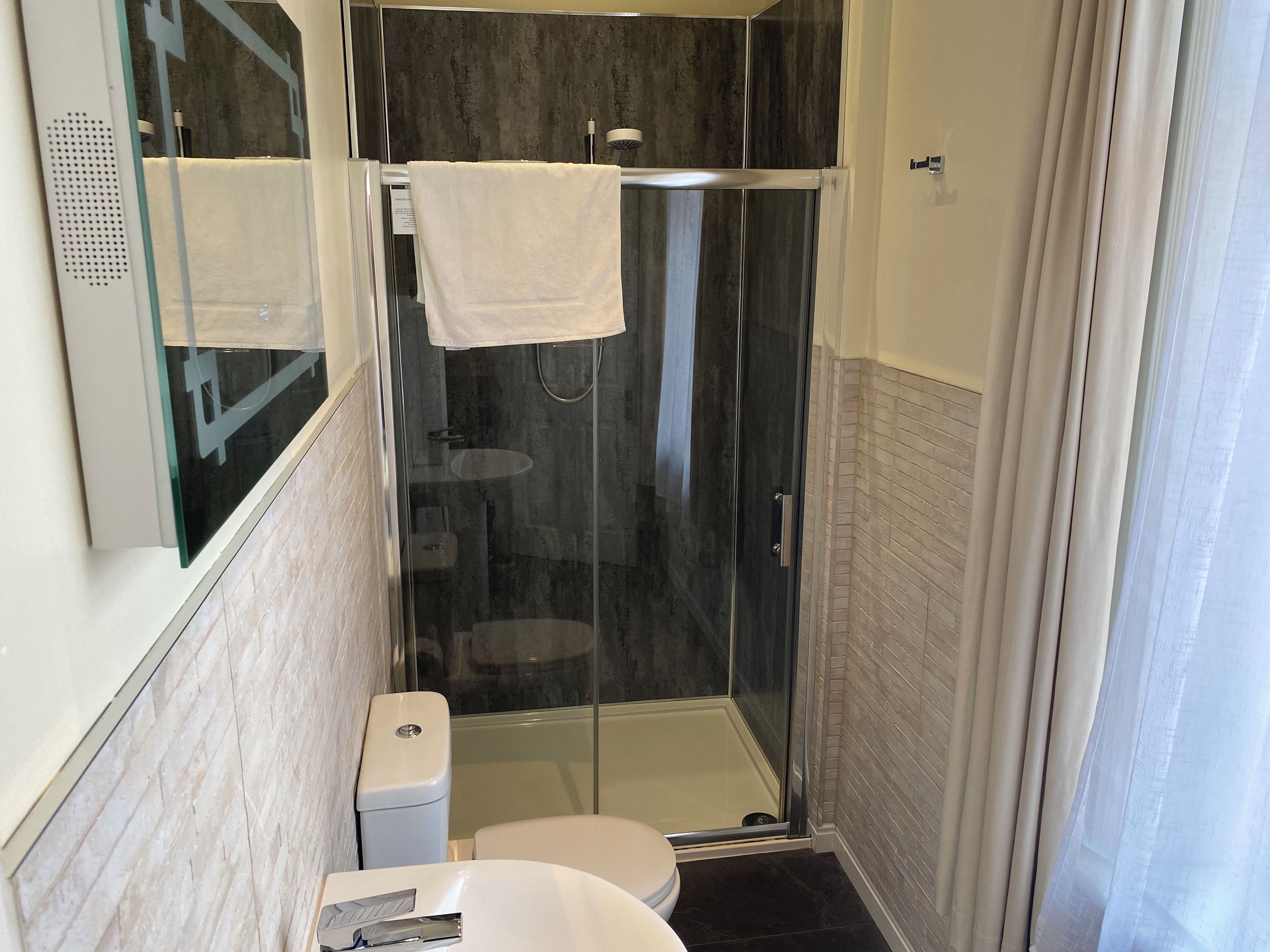 Un baño moderno con ducha envuelta en vidrio, inodoro blanco y lavamanos.