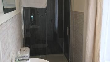 Un baño con un lavamanos blanco, cabina de ducha de vidrio y un inodoro.